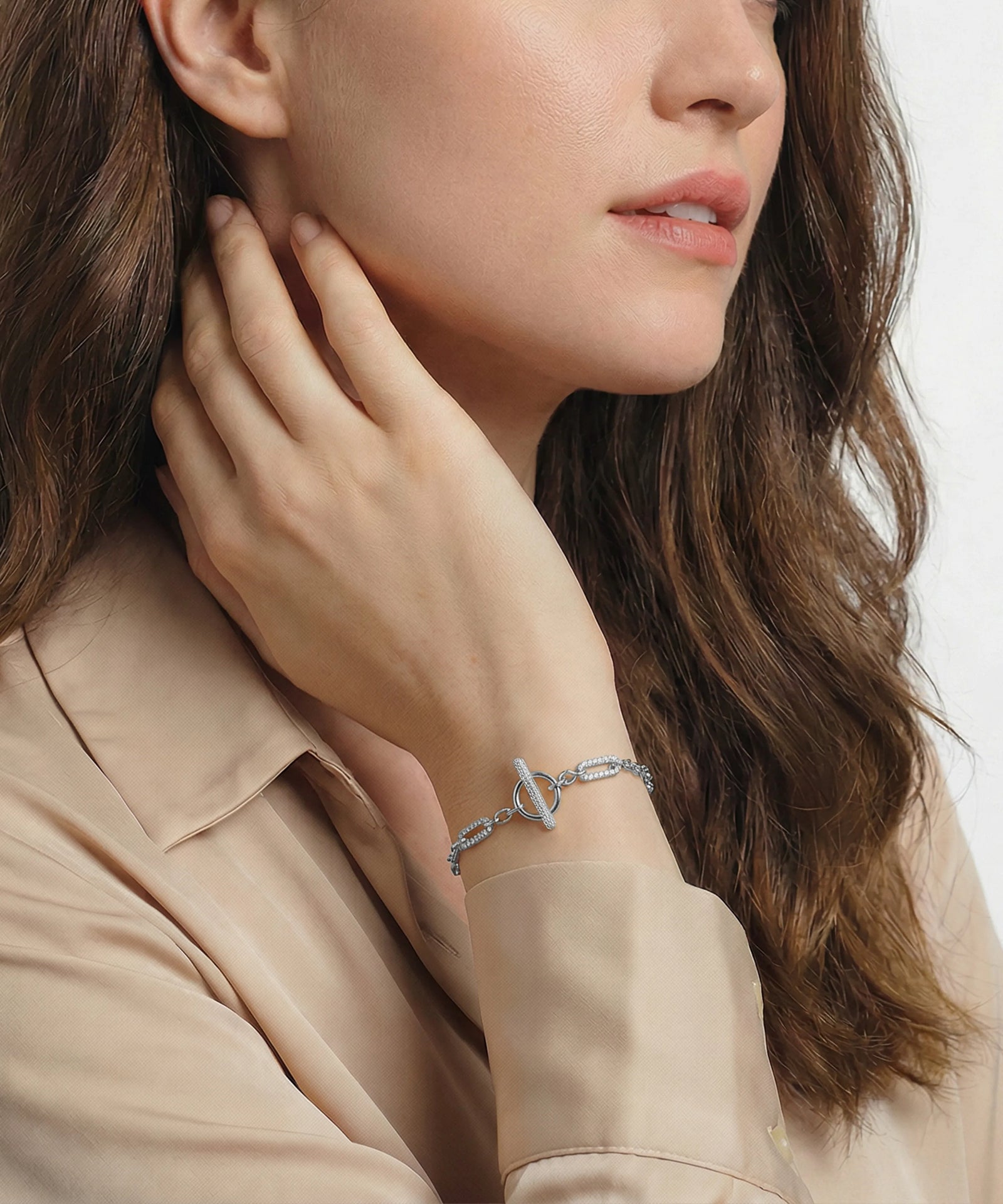 Woman wearing a silver bracelet on a plain background