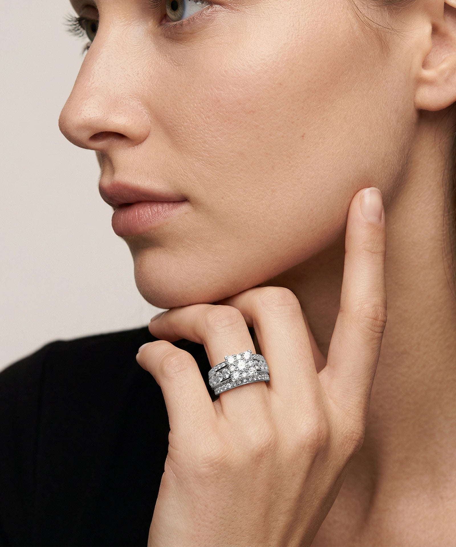 Close-up of a woman wearing a diamond ring on her finger against a neutral background