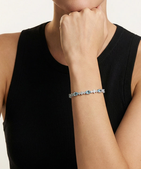 Person wearing a bracelet with blue stones on a plain background