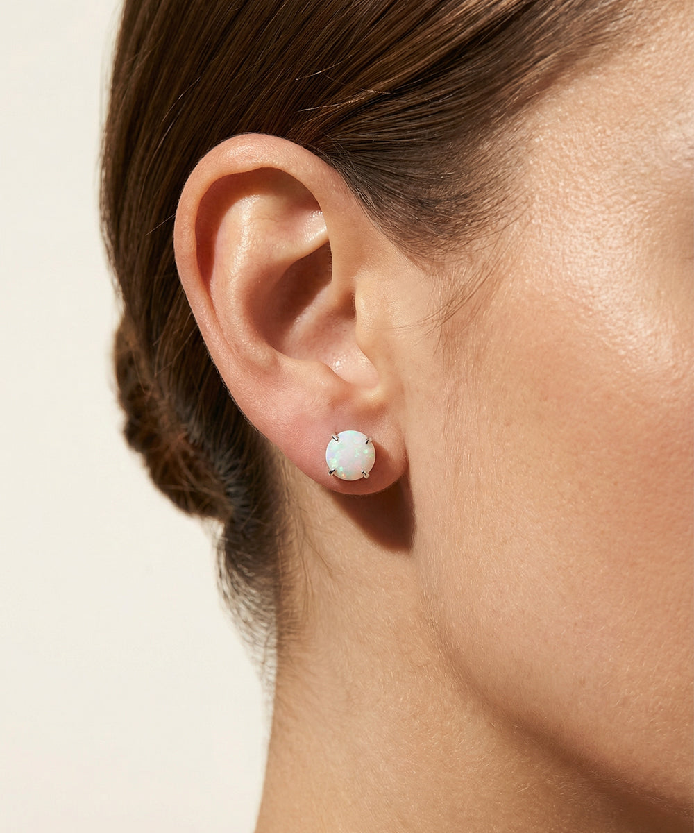 Close-up of an ear wearing a small round earring on a neutral background