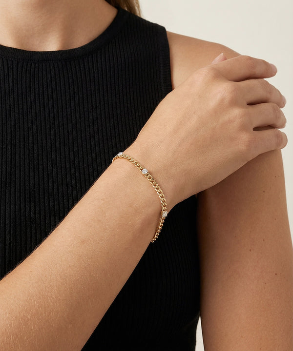 Gold bracelet on a person's wrist with a plain background