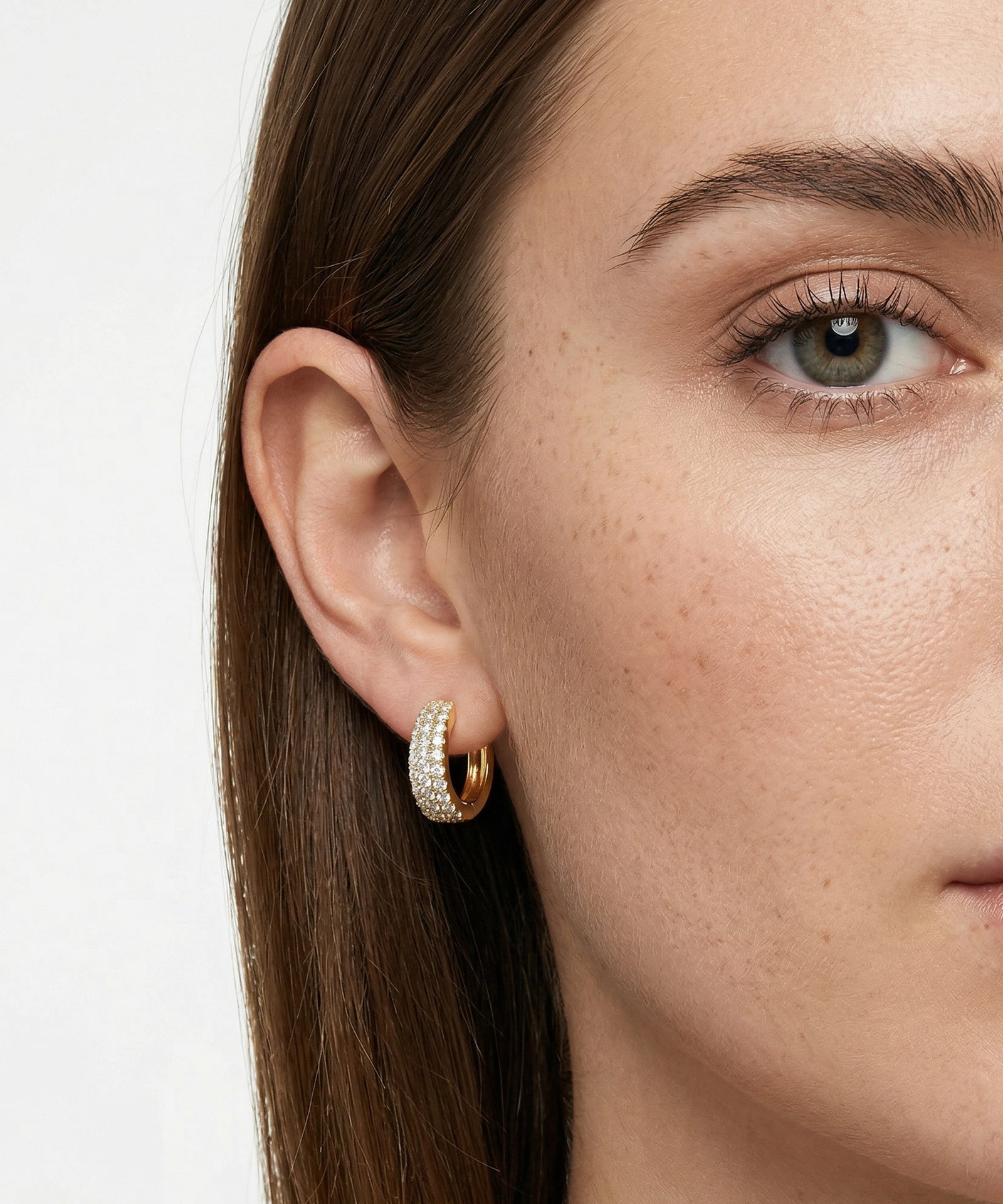 Close-up of a woman wearing gold hoop earrings with a blurred background