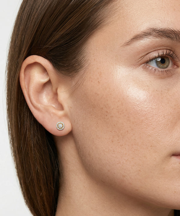 Close-up of a woman wearing a diamond earring on a plain background