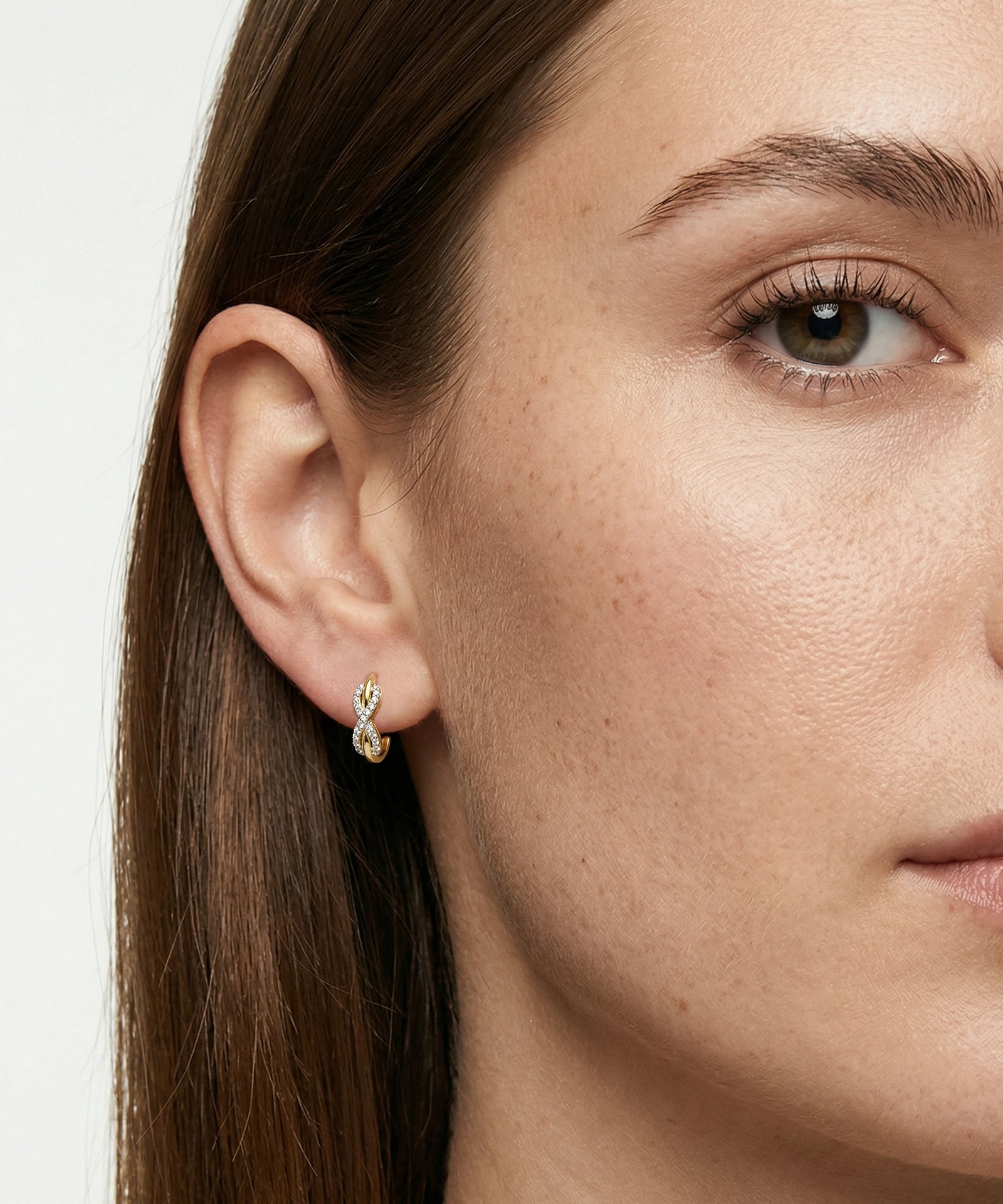 Close-up of a woman wearing a gold earring with a small gemstone.