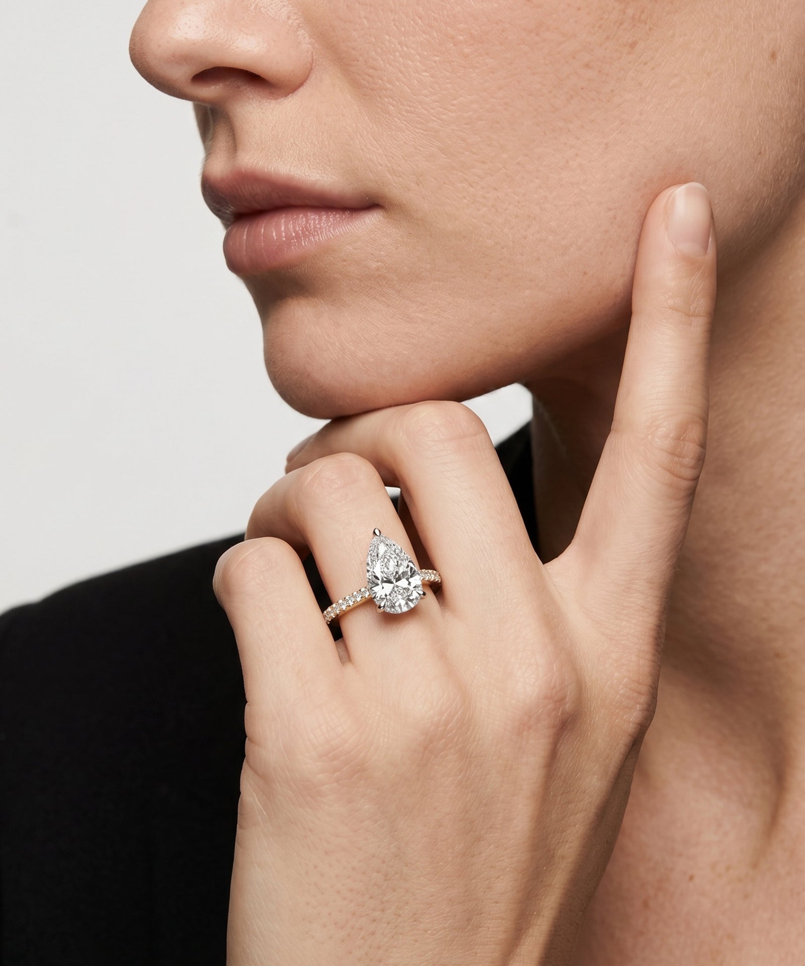 Close-up of a hand wearing a diamond ring with a neutral background