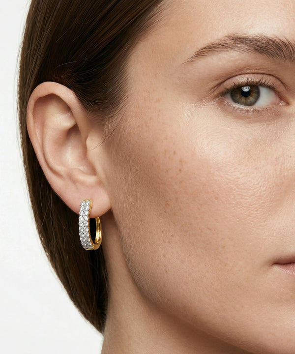 Close-up of a woman wearing silver hoop earrings with embedded stones.