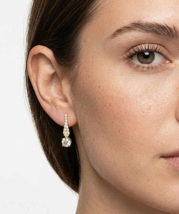 Close-up of a woman's face wearing a diamond earring on a white background