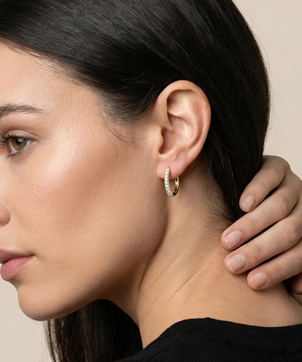 Close-up of a woman wearing a gold hoop earring with a neutral background
