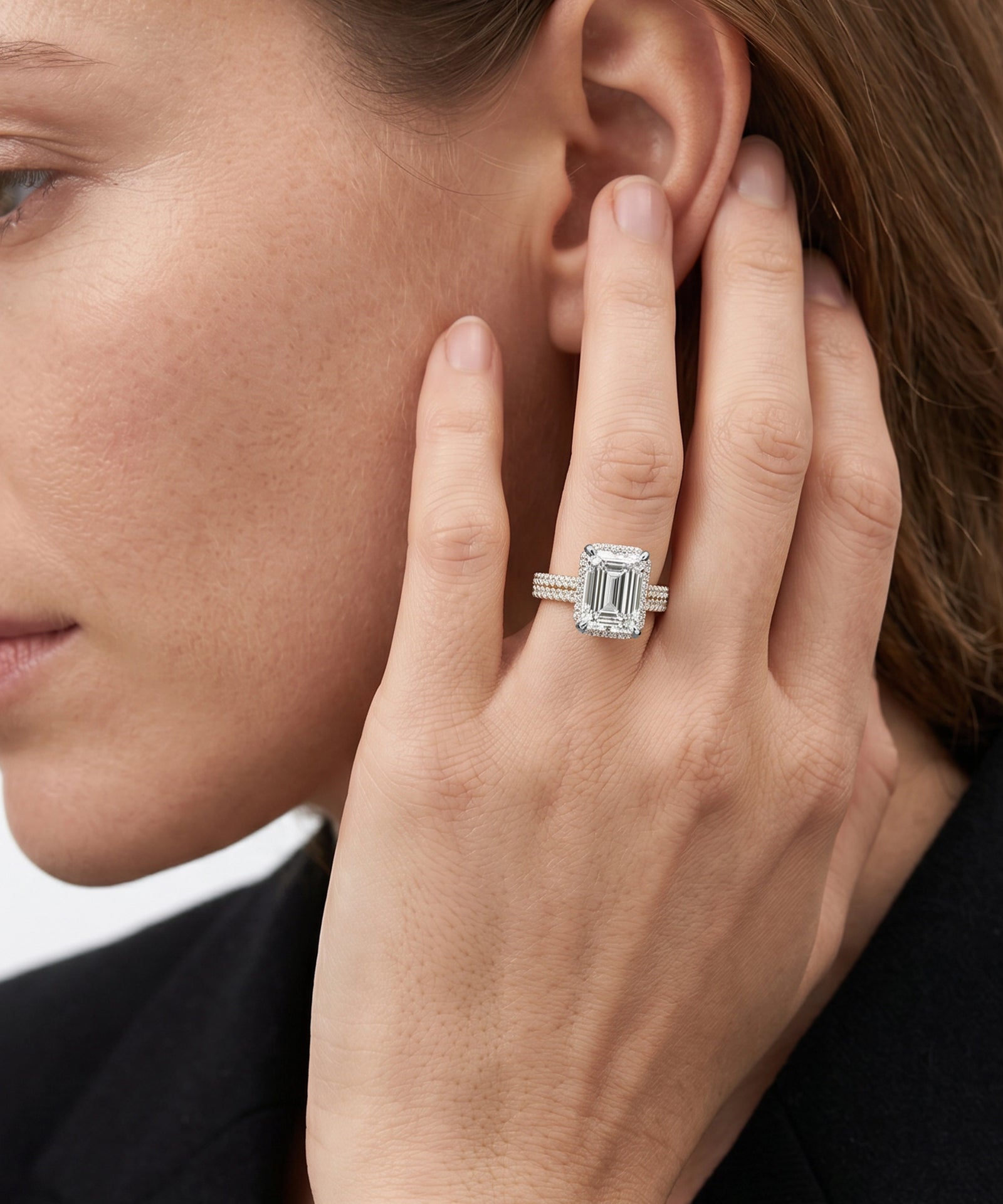 Close-up of a woman wearing a diamond ring on her hand near her ear.