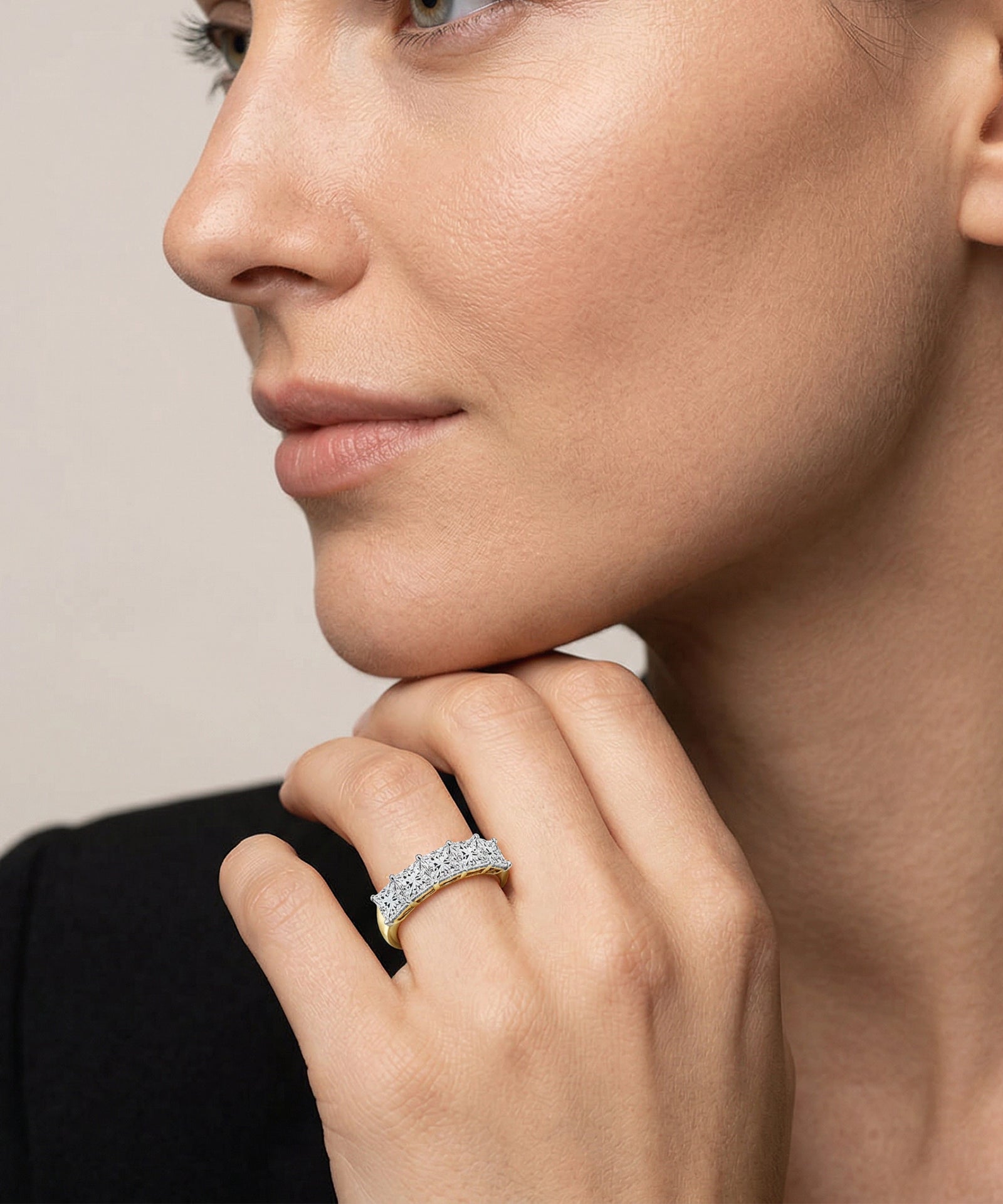 Close-up of a woman wearing a diamond ring on a neutral background