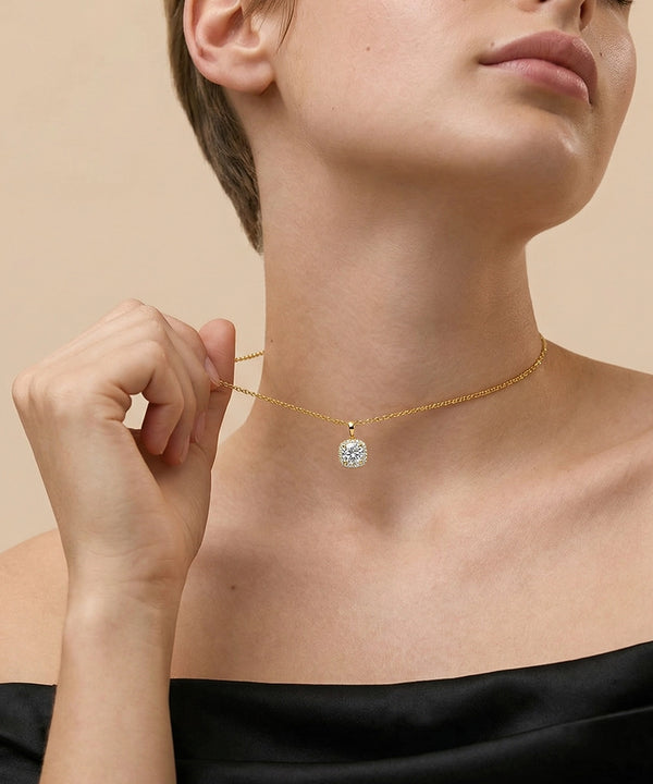 Woman wearing a gold necklace with a diamond pendant against a beige background