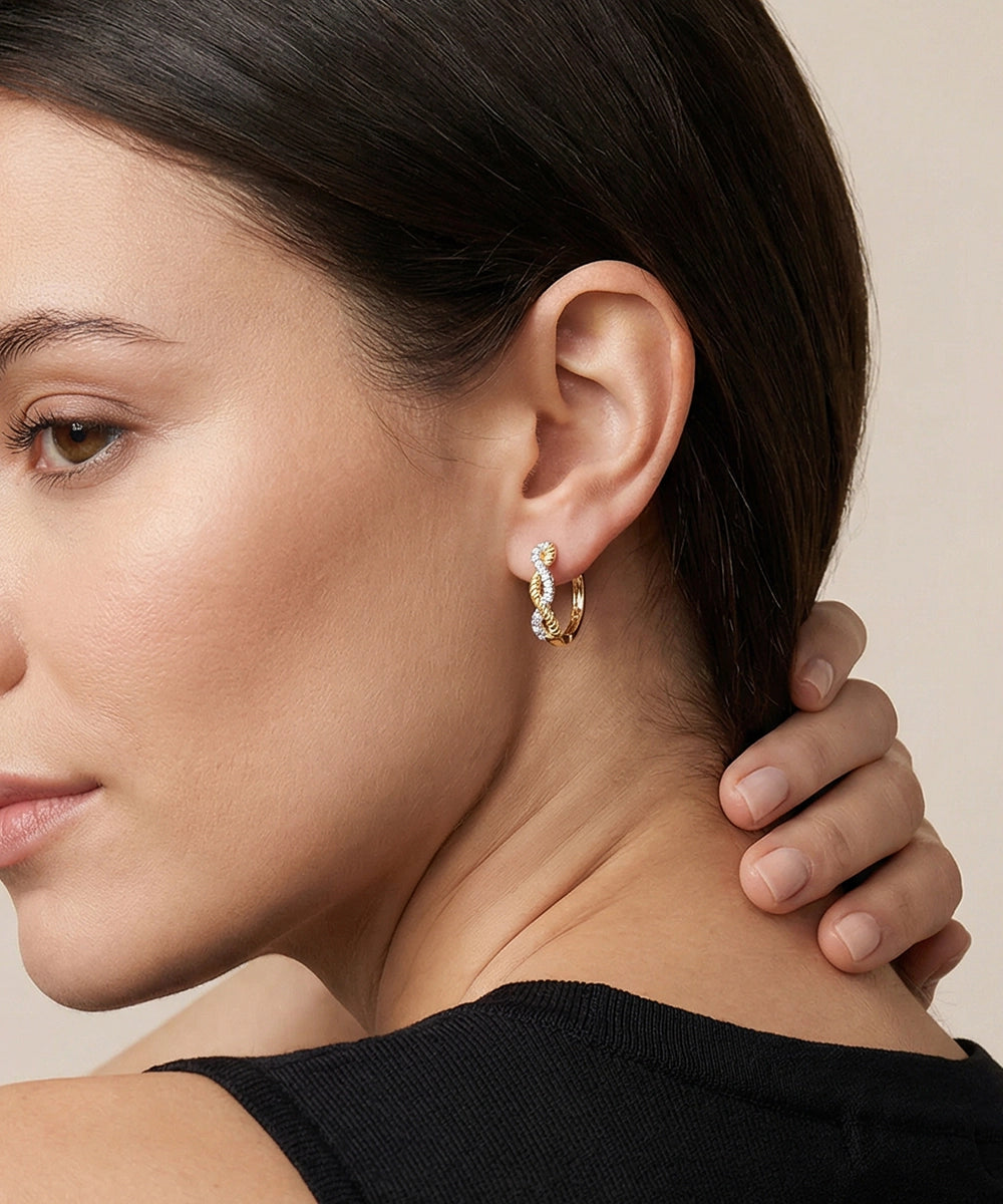 Close-up of a woman wearing gold hoop earrings with a neutral background