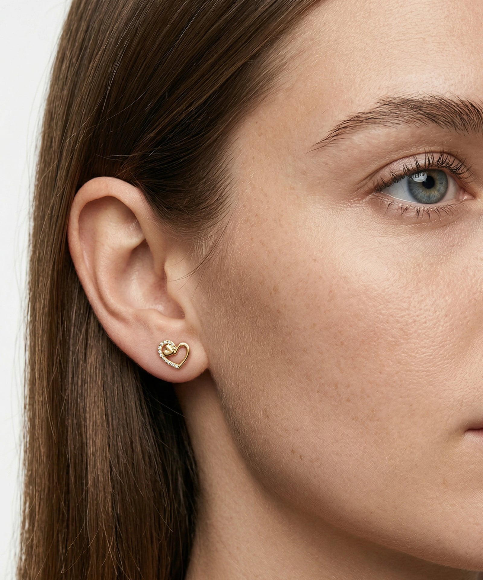 Close-up of a person wearing a gold heart-shaped earring.