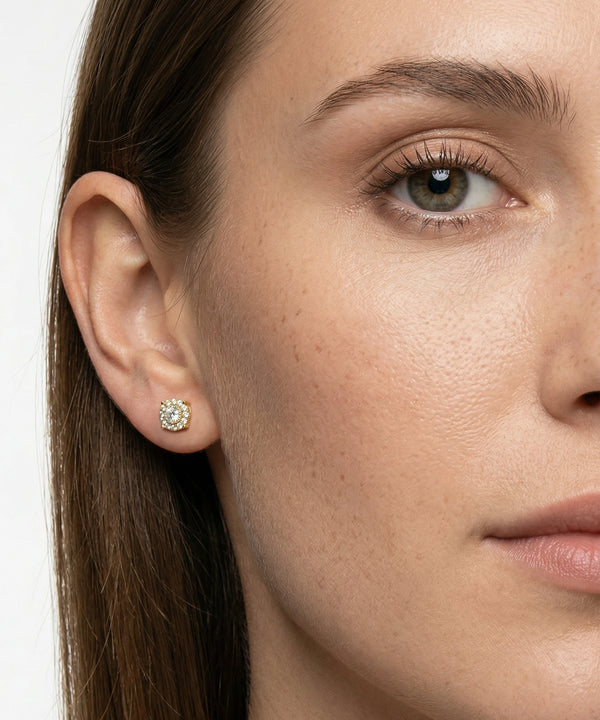 Close-up of a woman wearing a diamond earring on a plain background
