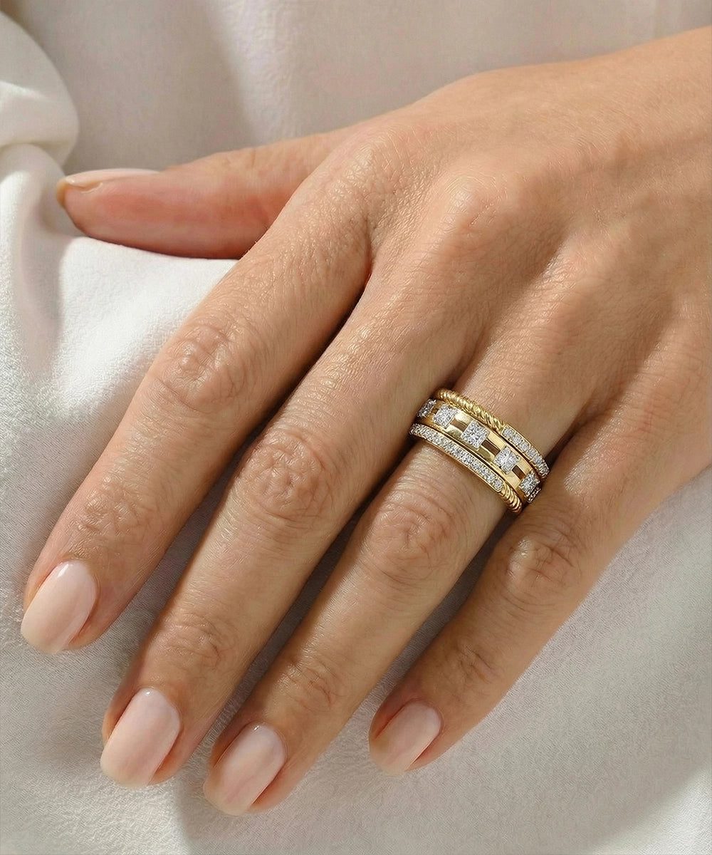 Hand wearing a gold and diamond ring on a light background