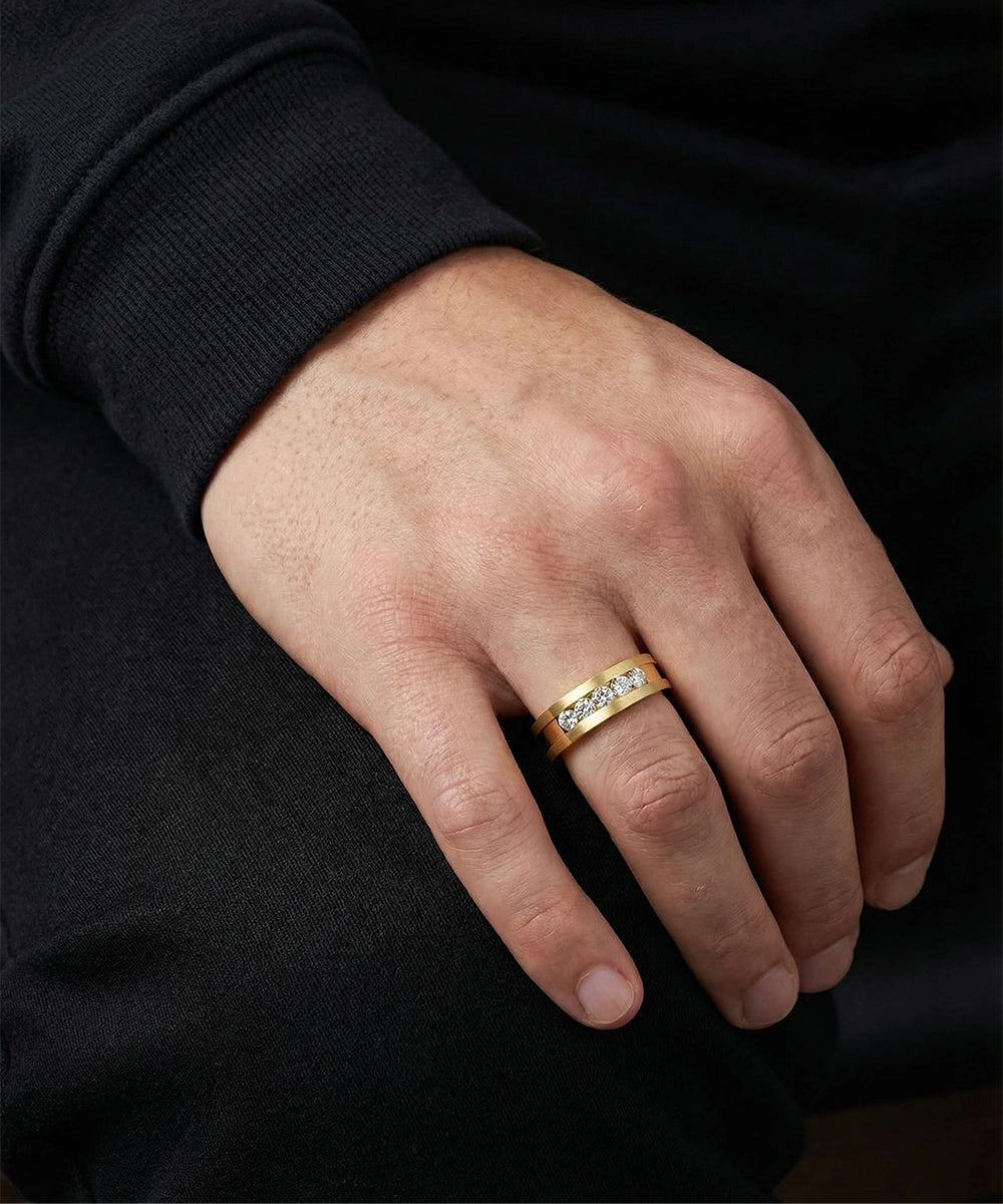 Hand wearing a gold ring with diamonds on a black background