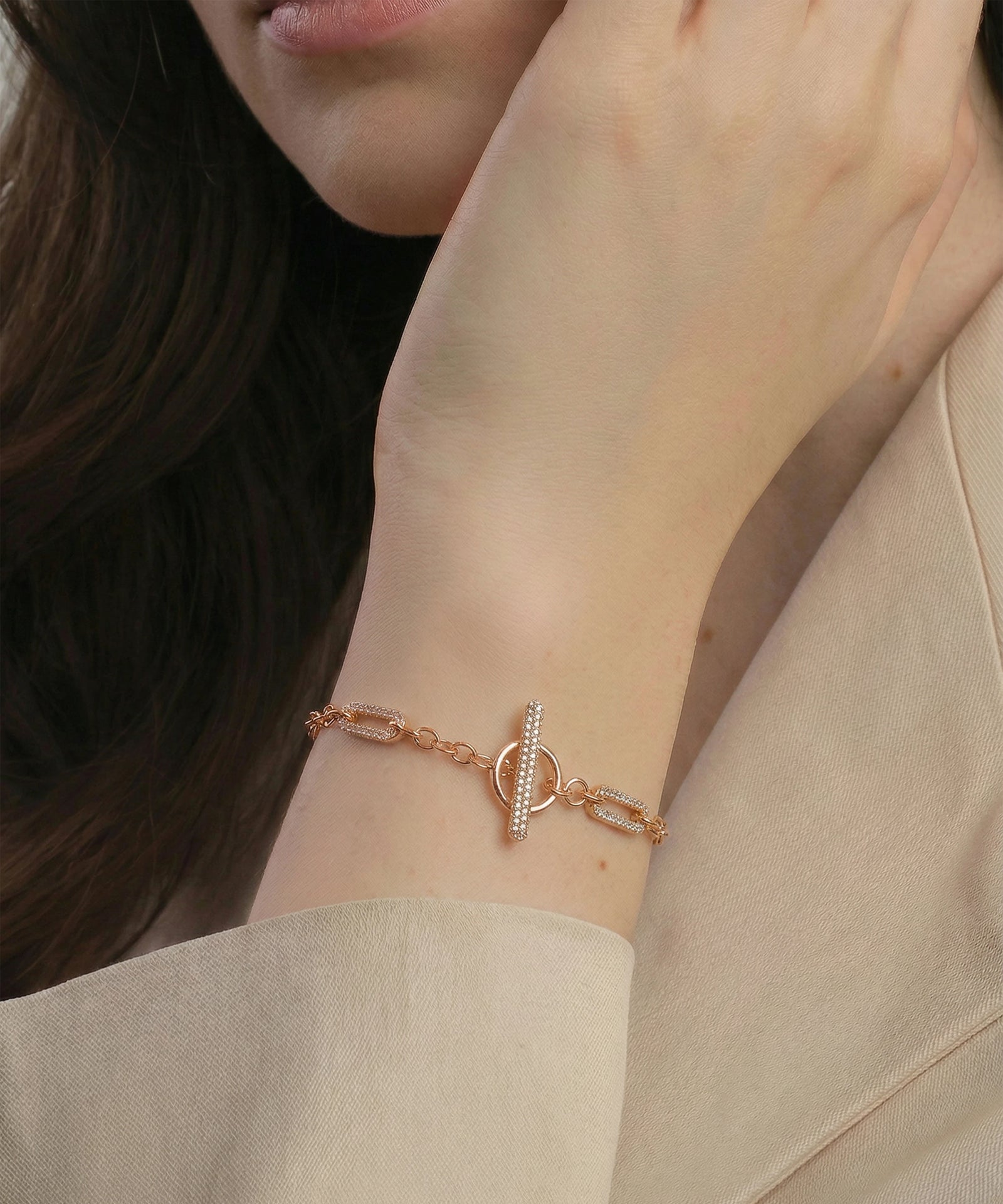 Rose gold bracelet on a person's wrist with a neutral background
