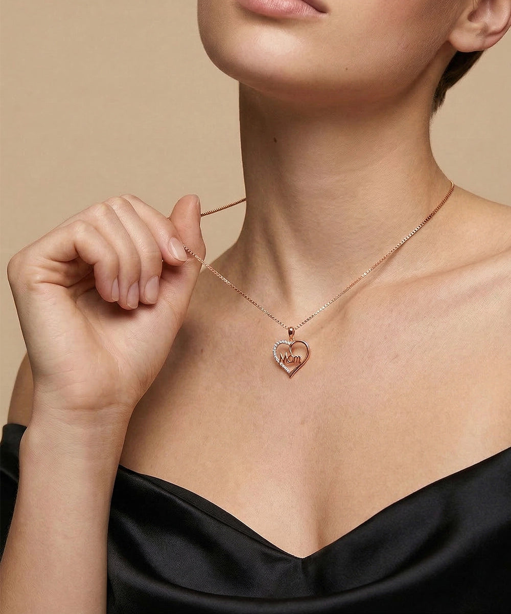 Necklace with a heart-shaped pendant featuring engraved text, worn by a person against a neutral background.