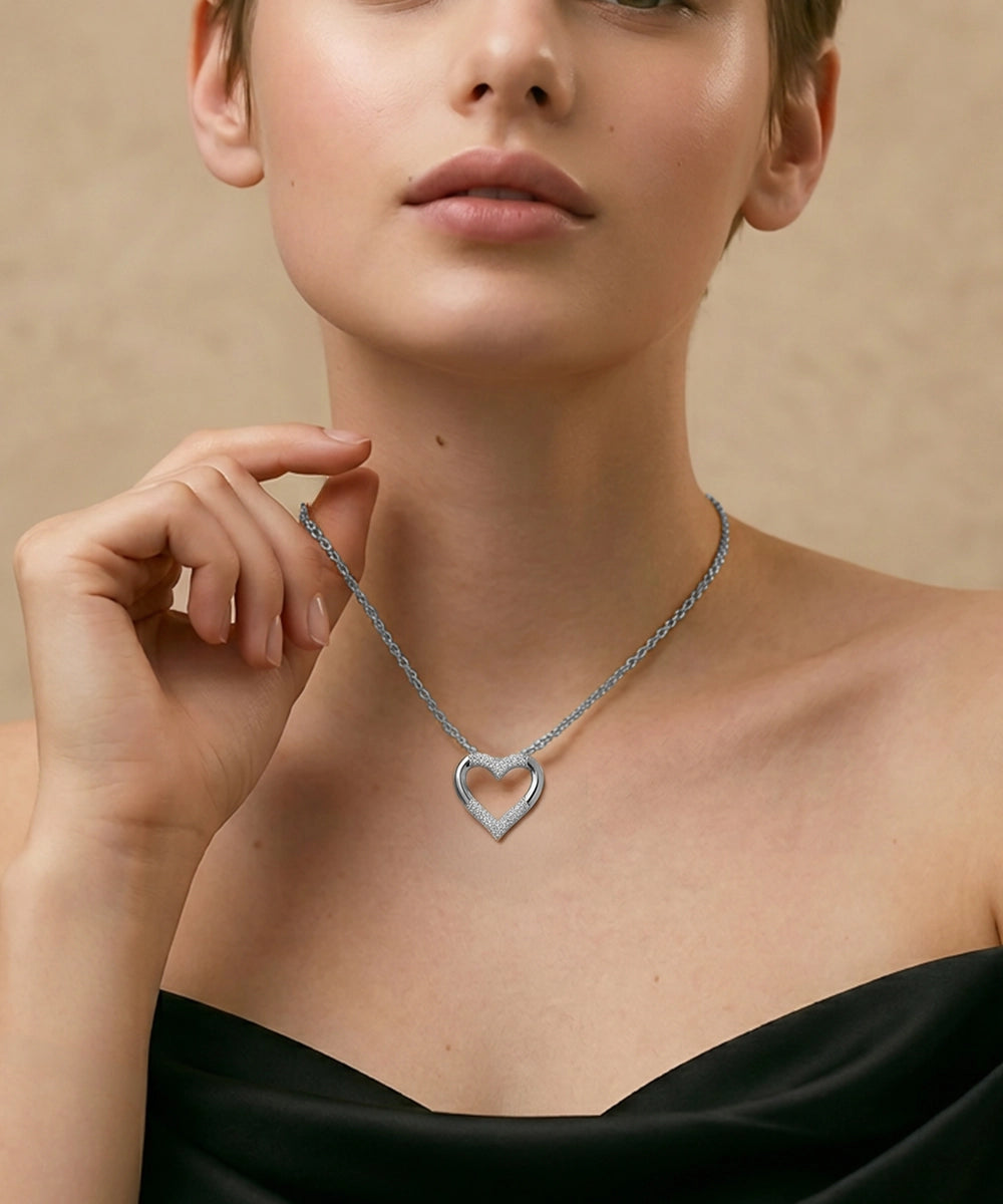 Woman wearing a silver heart-shaped necklace against a beige background