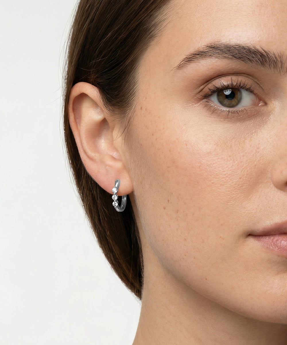 Close-up of a woman wearing a silver earring on a plain background