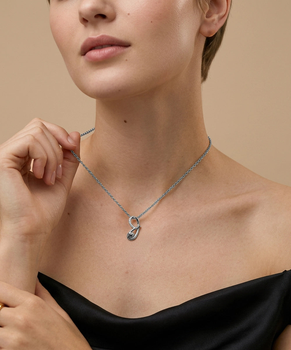 Woman wearing a silver necklace with a heart pendant against a beige background