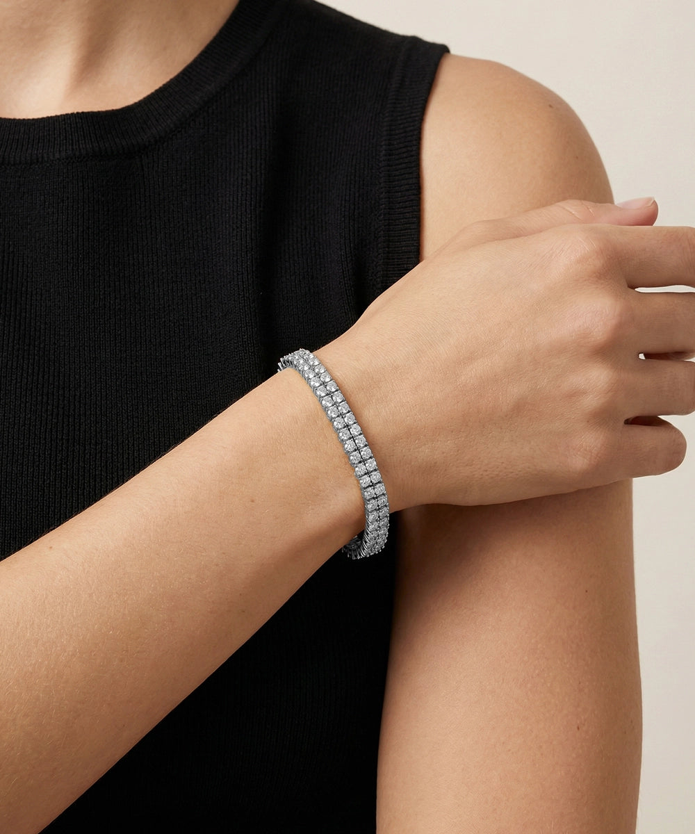 Person wearing a silver bracelet on a neutral background