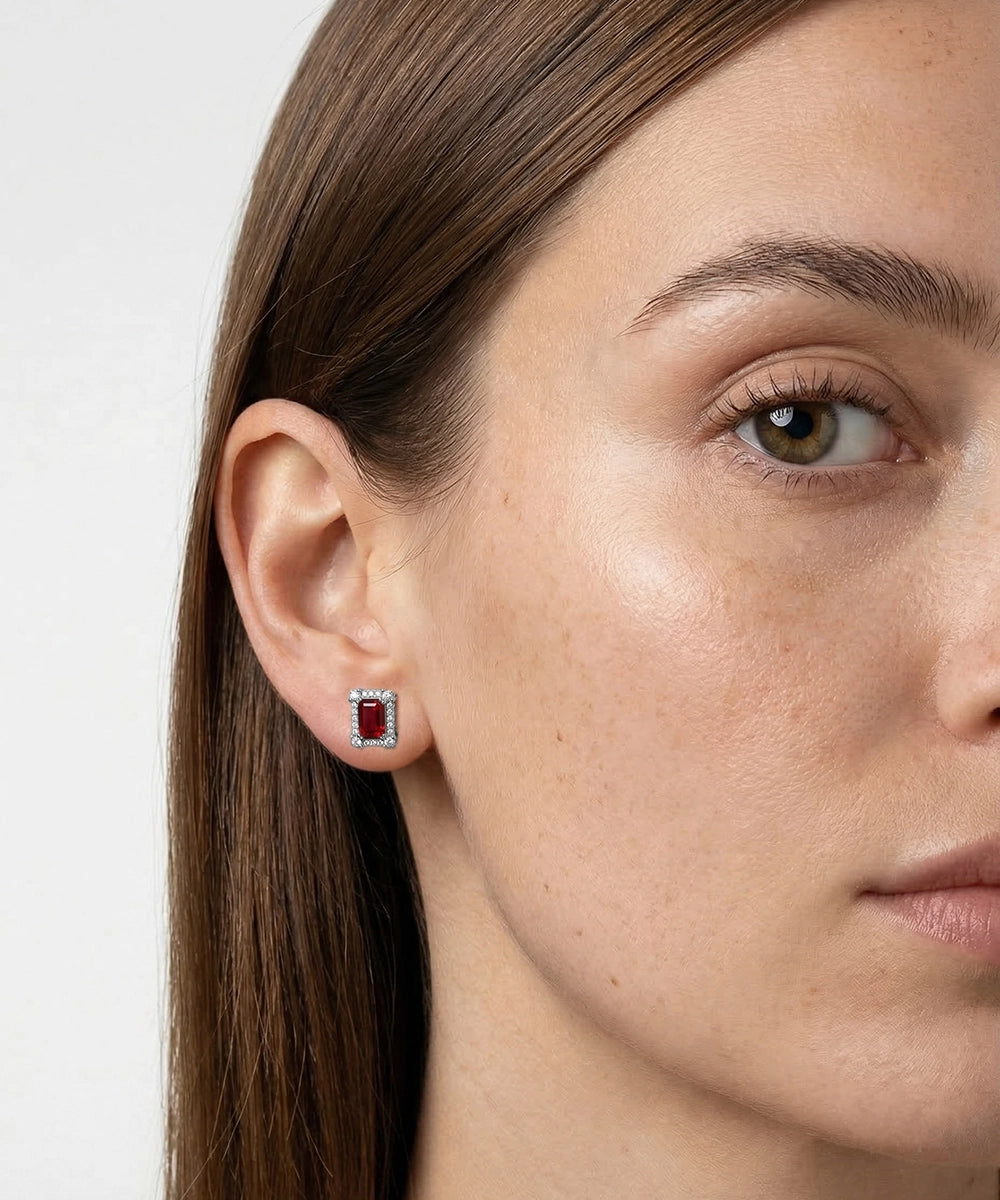 Close-up of a woman wearing a red gemstone earring with a white background