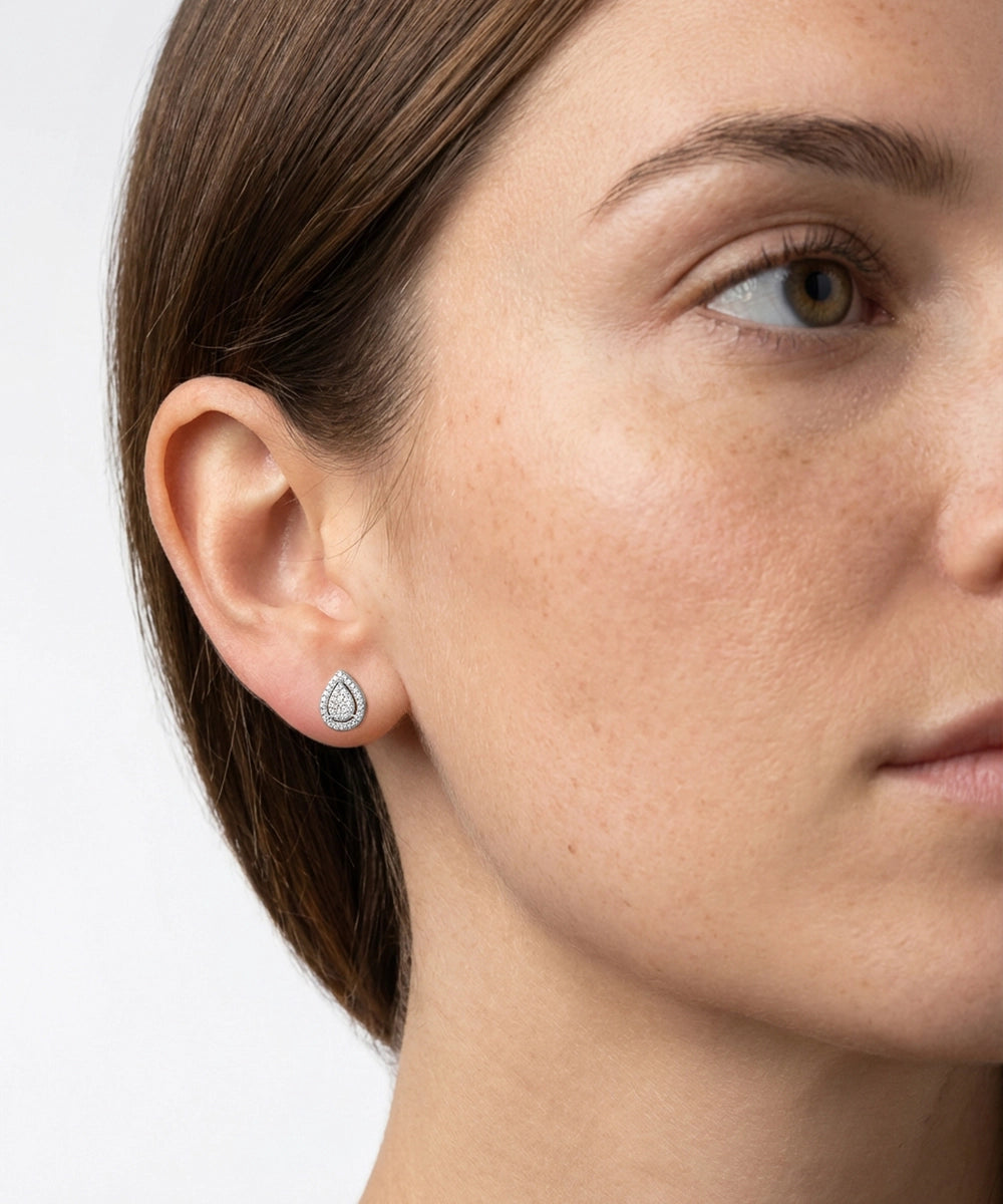 Close-up of a woman wearing a teardrop-shaped earring on a white background