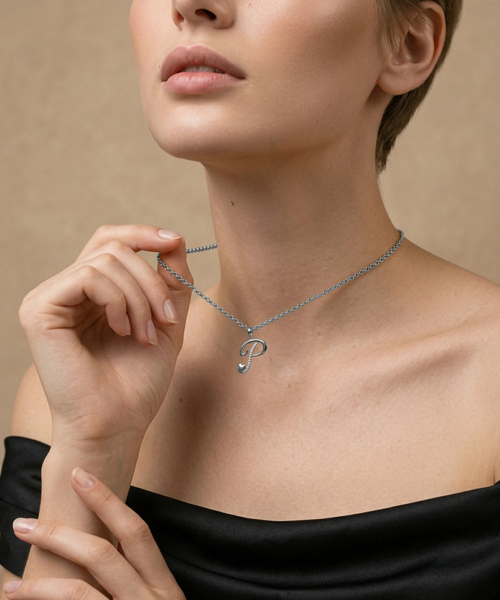 Woman wearing a silver necklace with a heart pendant against a beige background