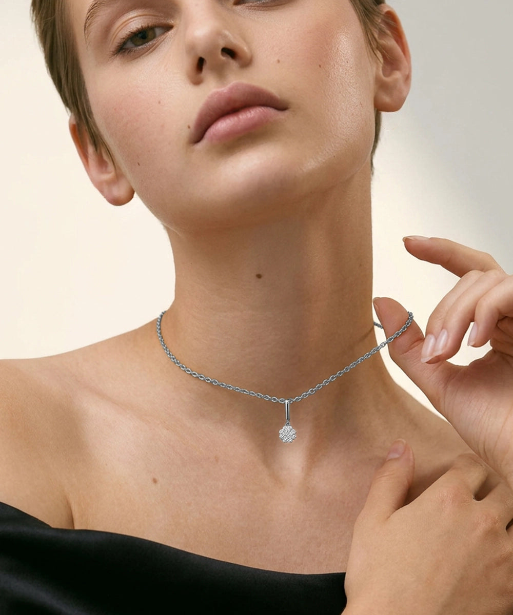 Close-up of a woman wearing a silver necklace with a diamond pendant on a beige background