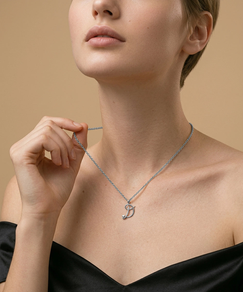 Woman wearing a silver necklace with a pendant against a beige background