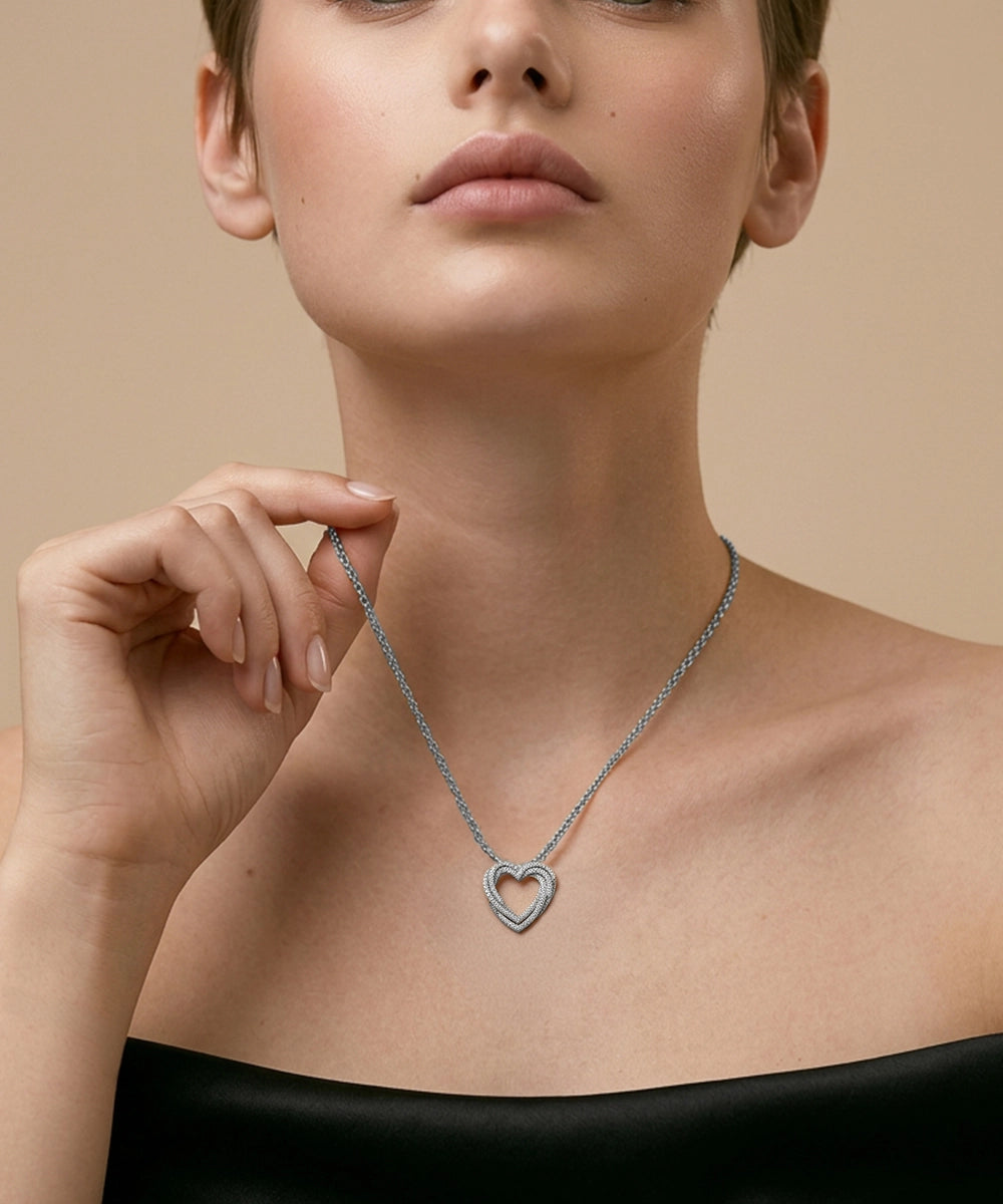 Woman wearing a silver necklace with a heart pendant against a beige background