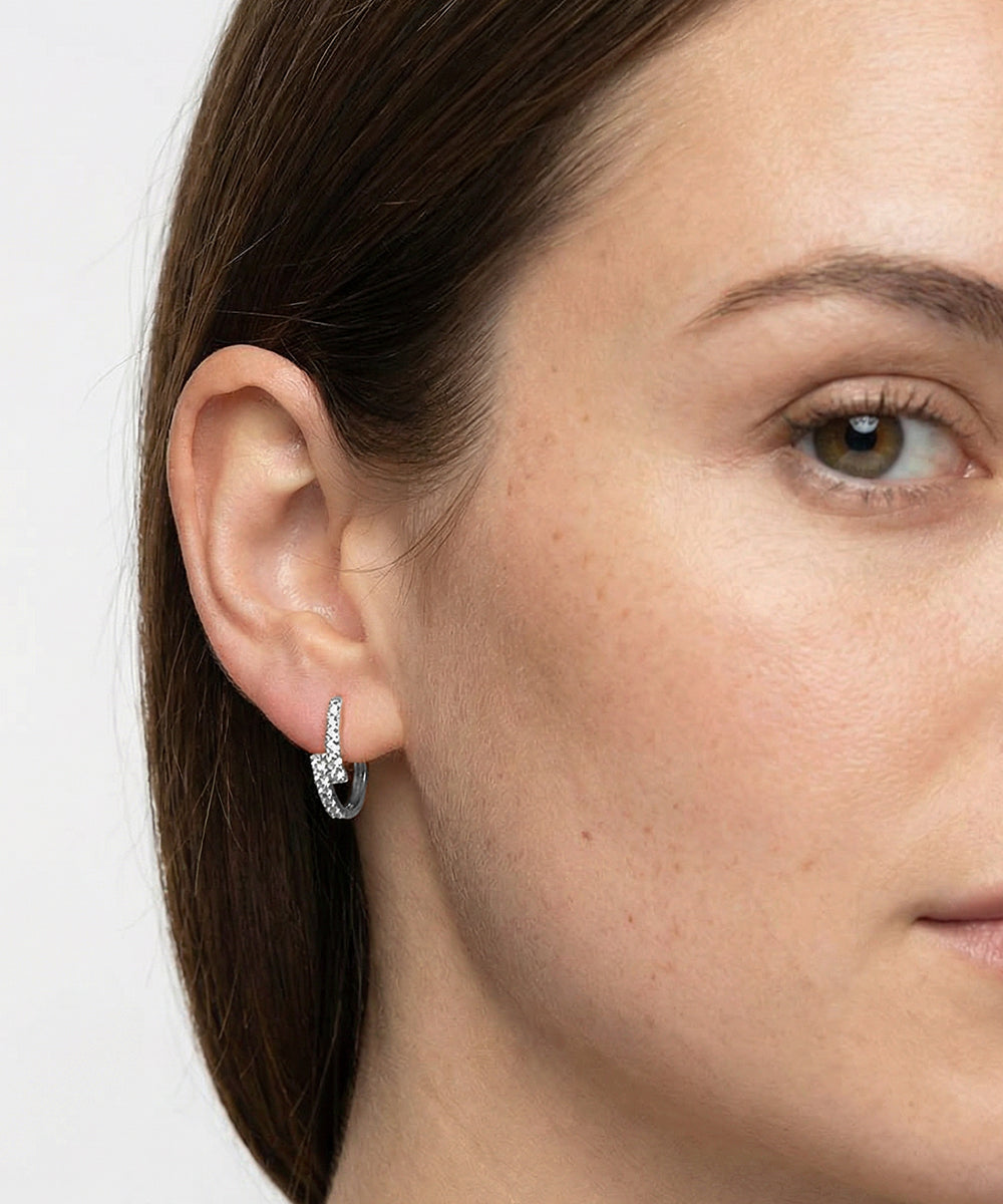 Close-up of a woman wearing a silver earring with a black gemstone on a white background