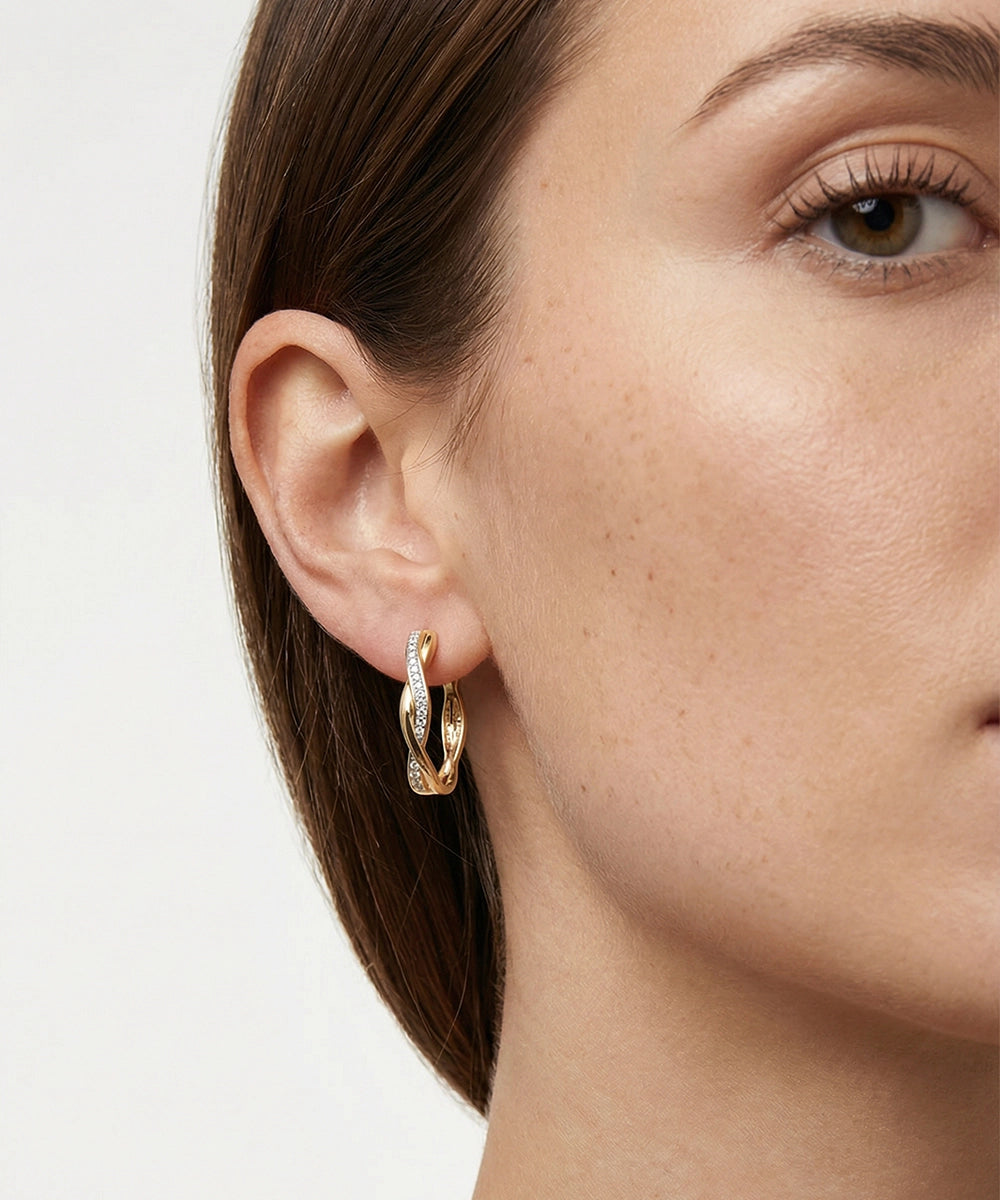 Close-up of a woman wearing gold hoop earrings on a plain background