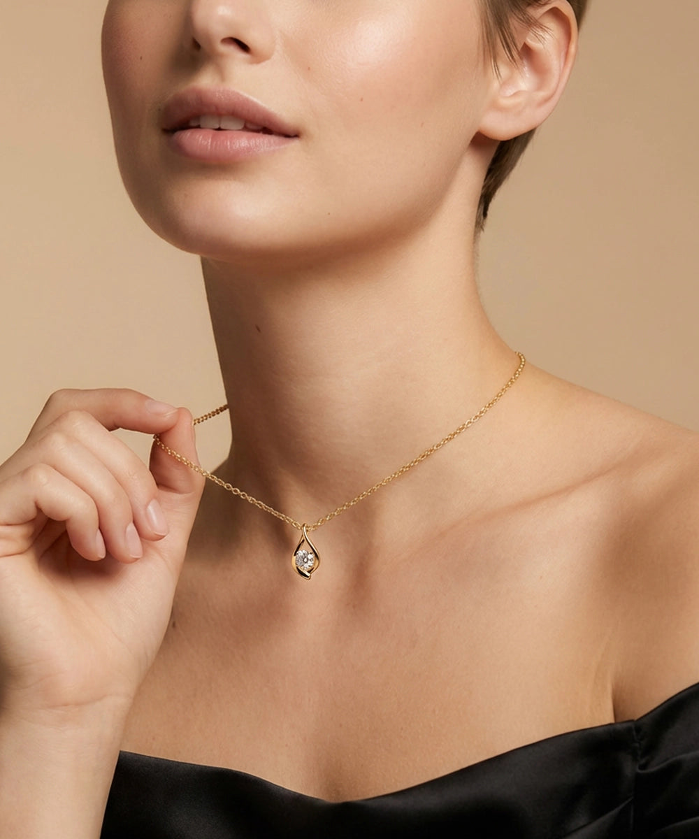 Woman wearing a gold necklace with a pendant against a beige background