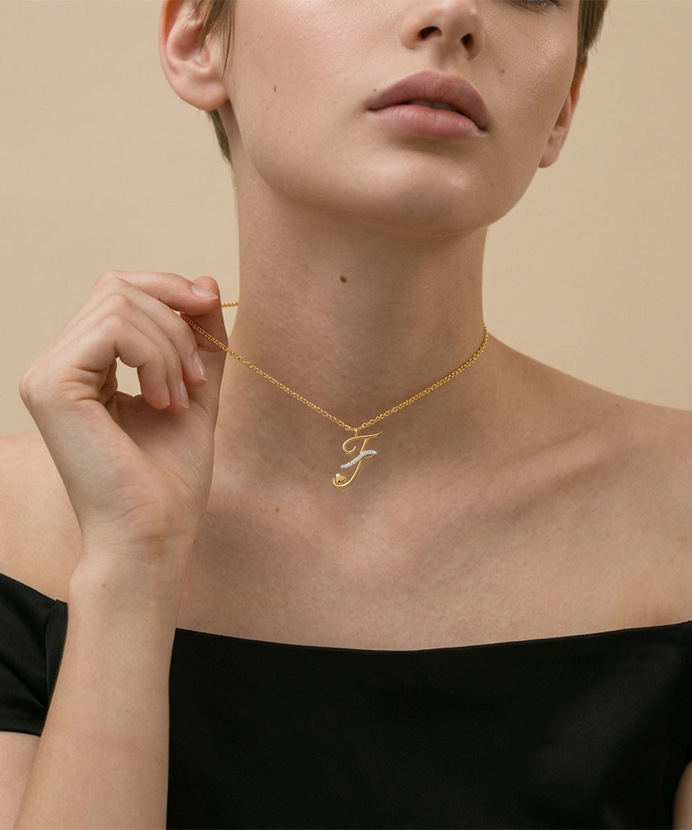 Gold necklace with a letter 'F' pendant worn by a model against a beige background