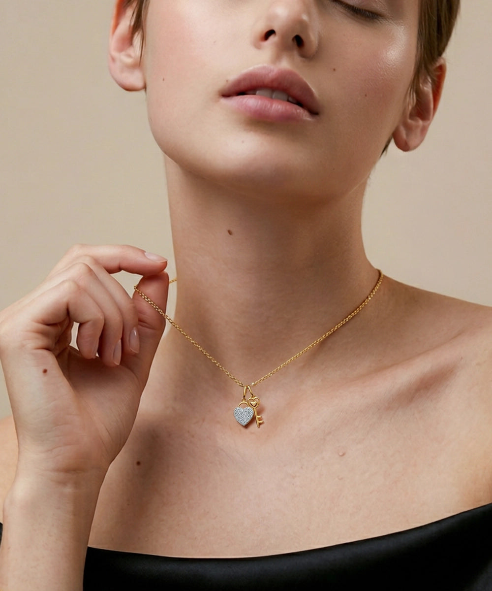 Woman wearing a gold necklace with a heart-shaped pendant against a neutral background