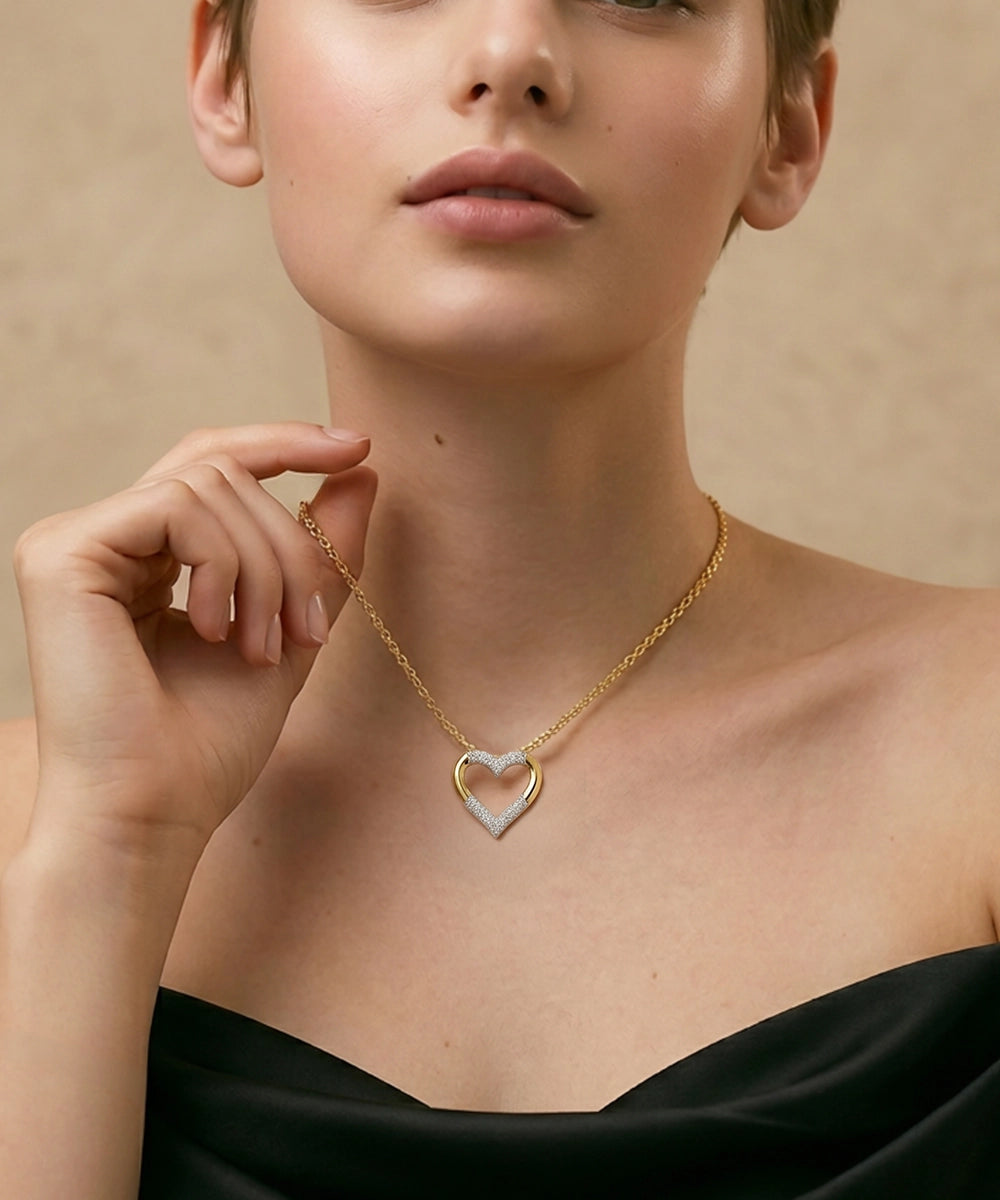 Woman wearing a gold necklace with a heart-shaped pendant against a beige background