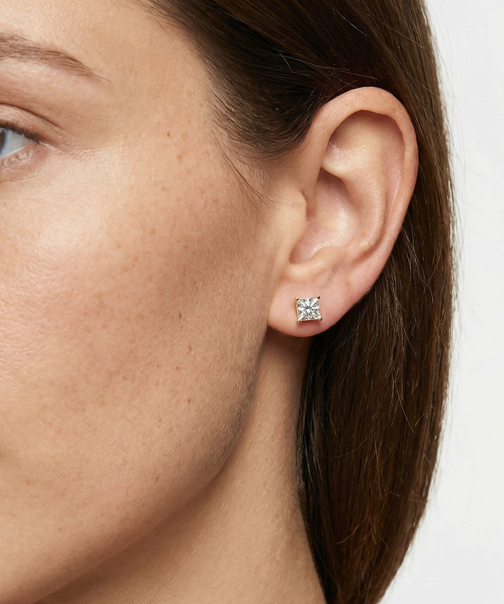 Close-up of a woman wearing a diamond stud earring on a white background