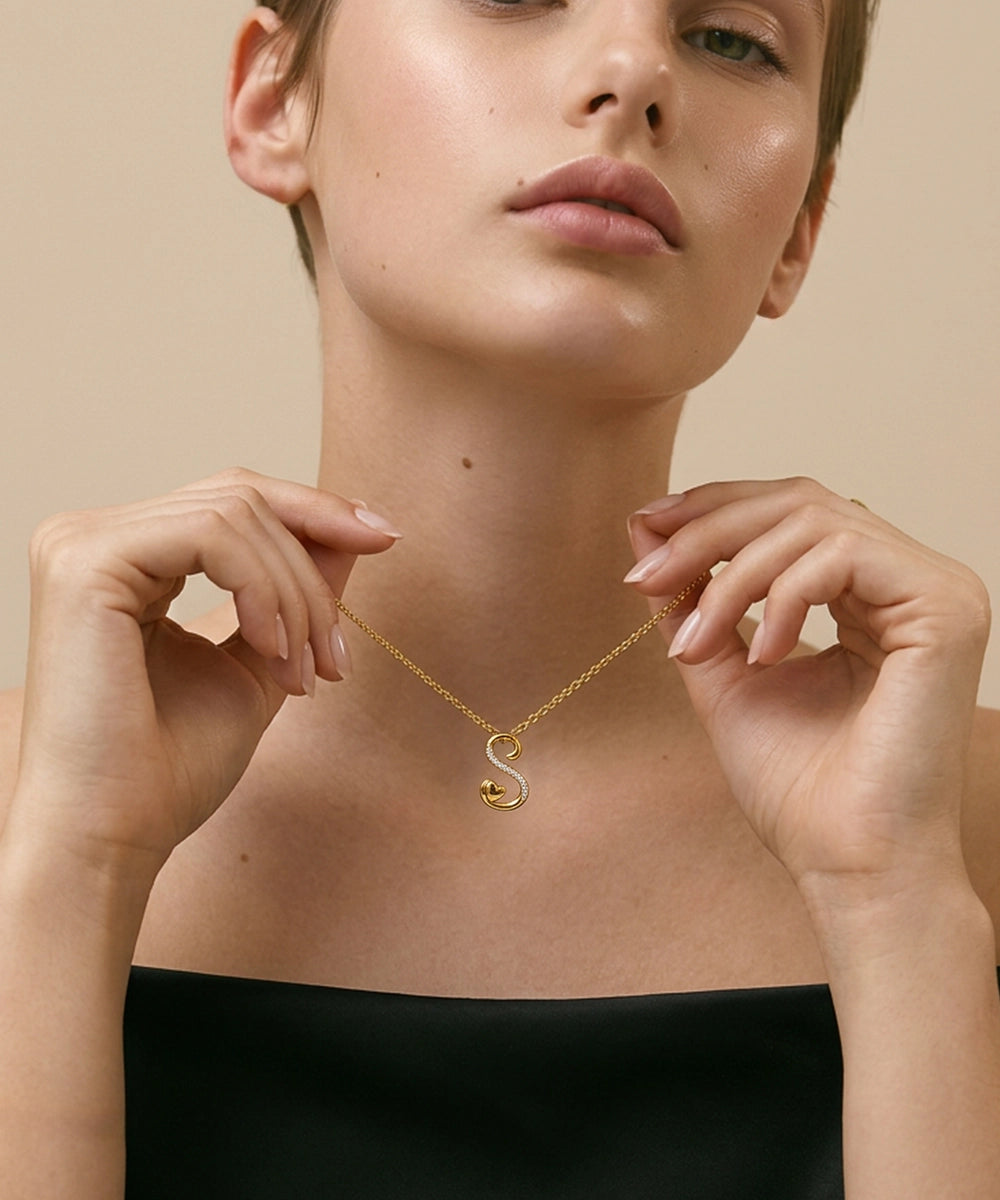 Woman wearing a gold necklace with a heart pendant against a beige background