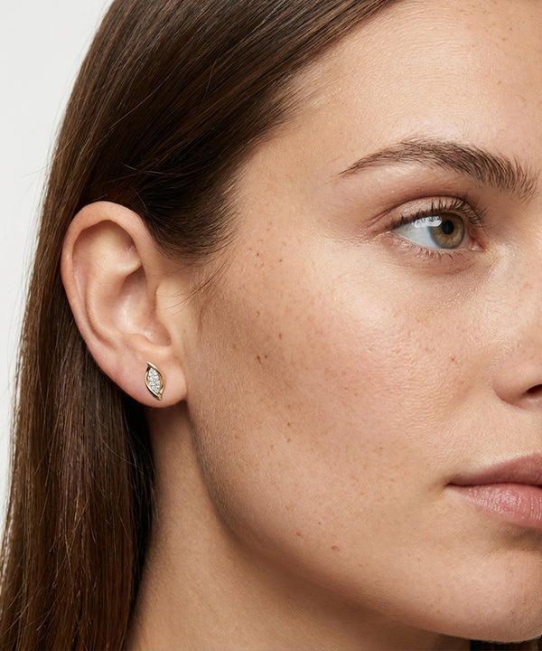 Close-up of a woman wearing a diamond earring with a neutral background