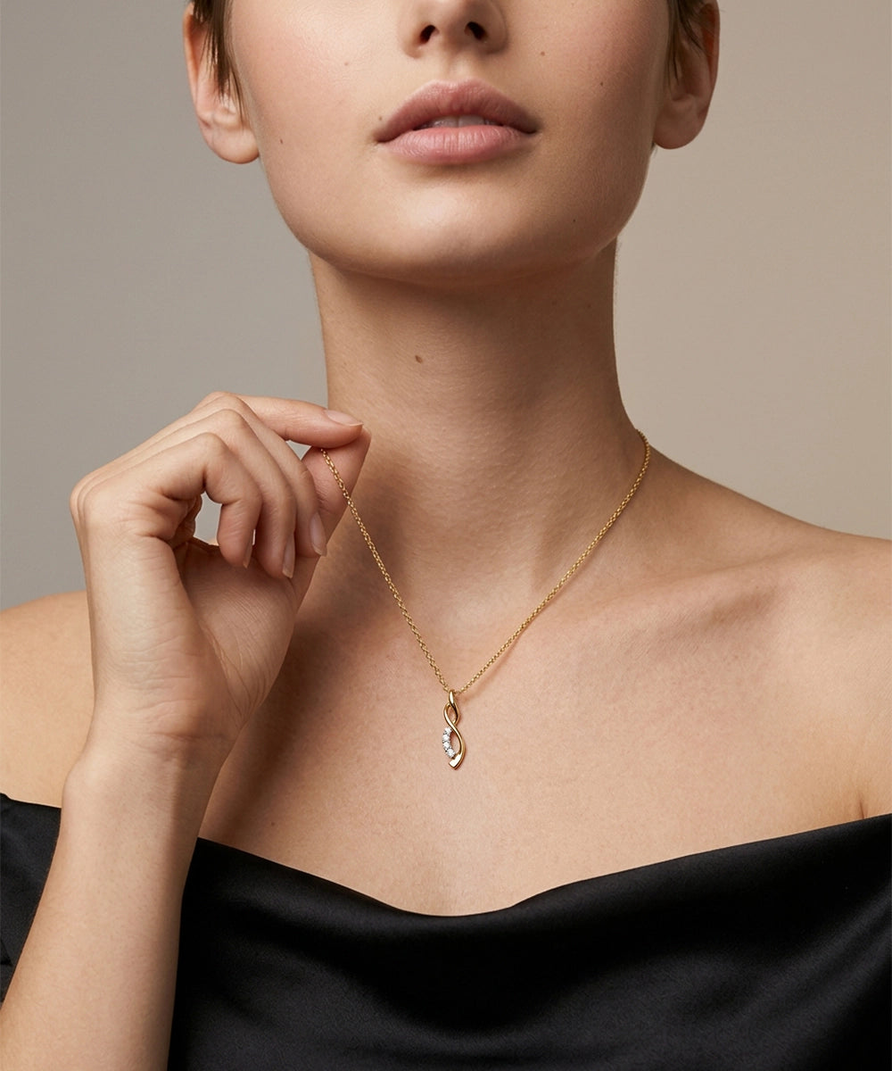 Woman wearing a silver necklace with a black top against a neutral background