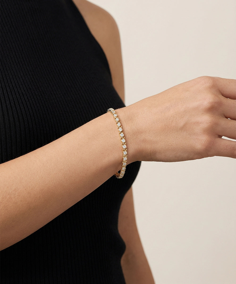 Gold bracelet on a person's wrist against a neutral background