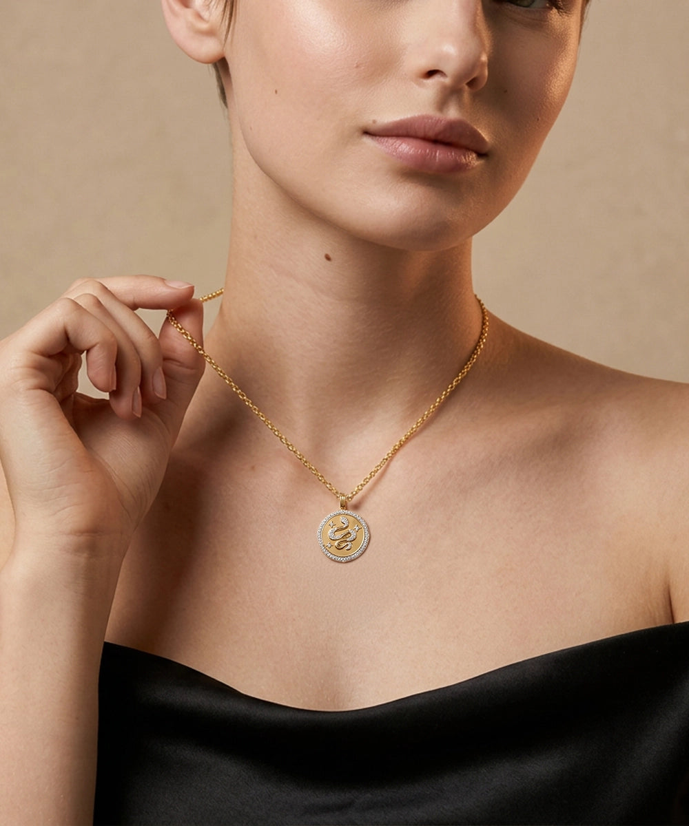 Woman wearing a gold necklace with a circular pendant against a beige background