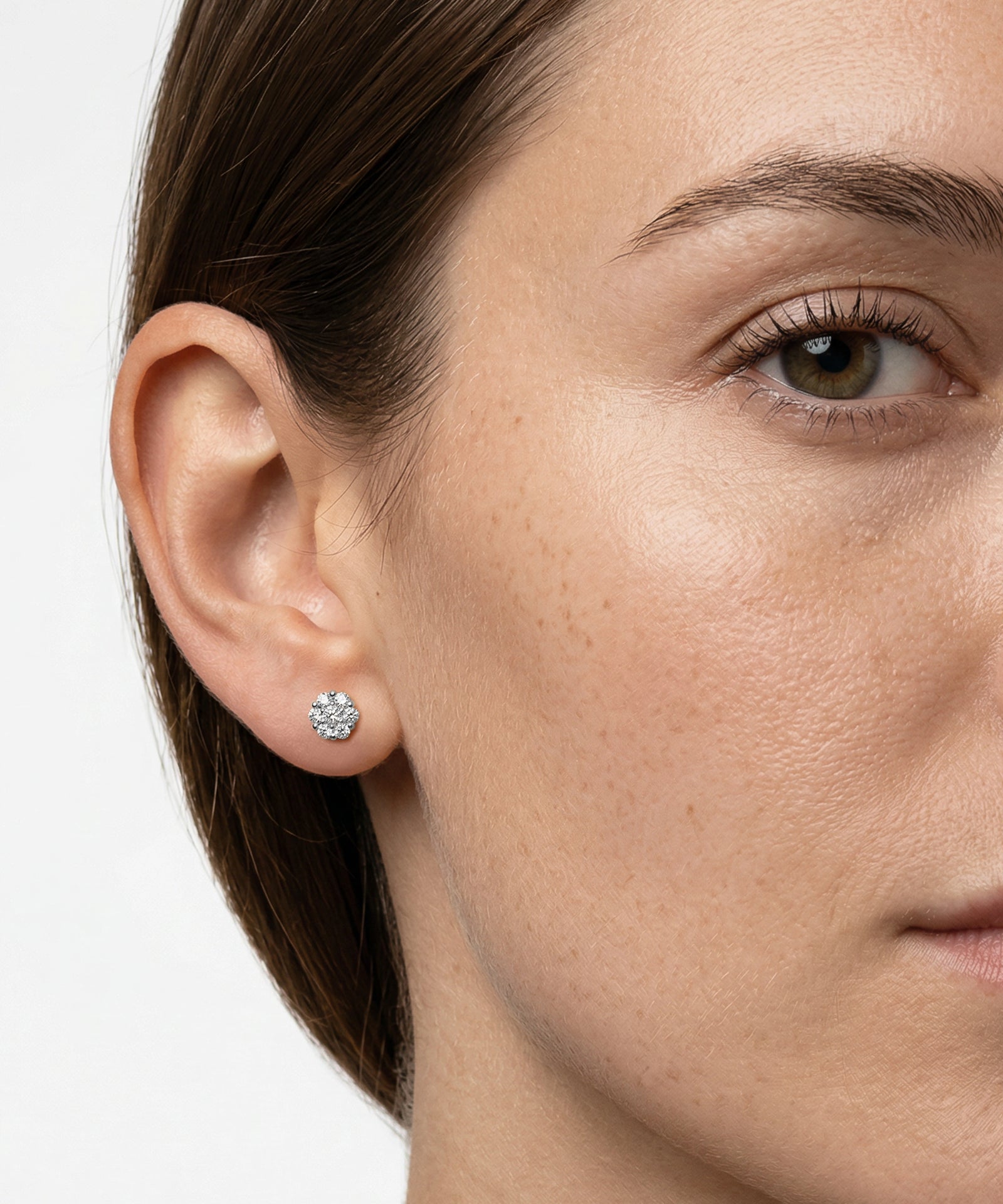 Close-up of a woman wearing a diamond earring on a white background