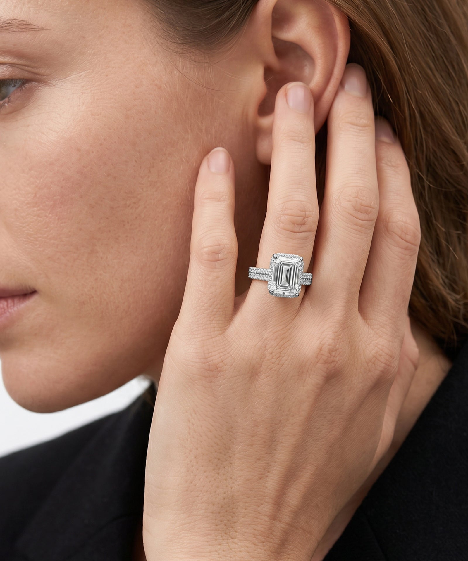 Close-up of a woman wearing a diamond ring on her hand near her ear.