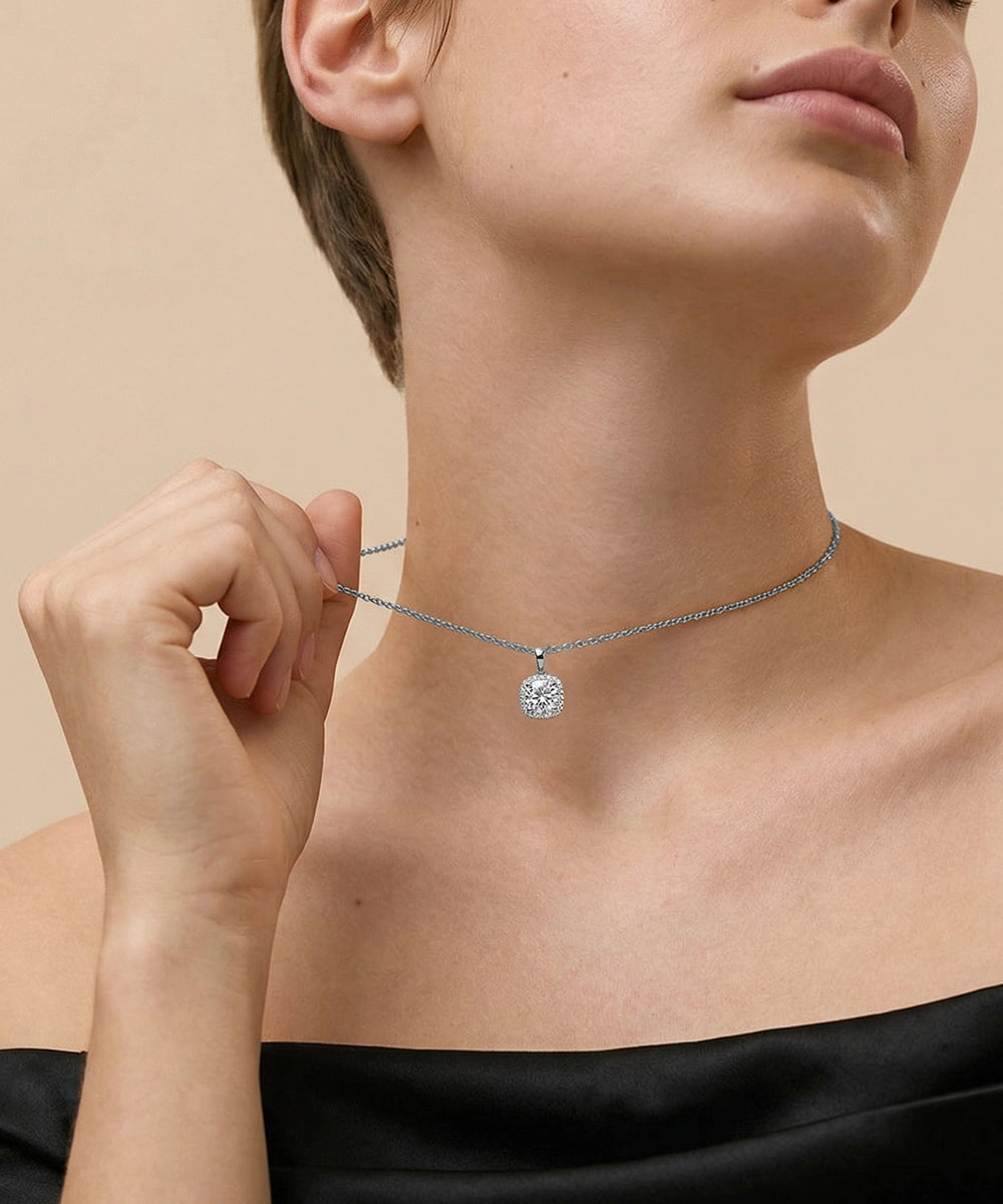 Woman wearing a gold necklace with a diamond pendant against a beige background