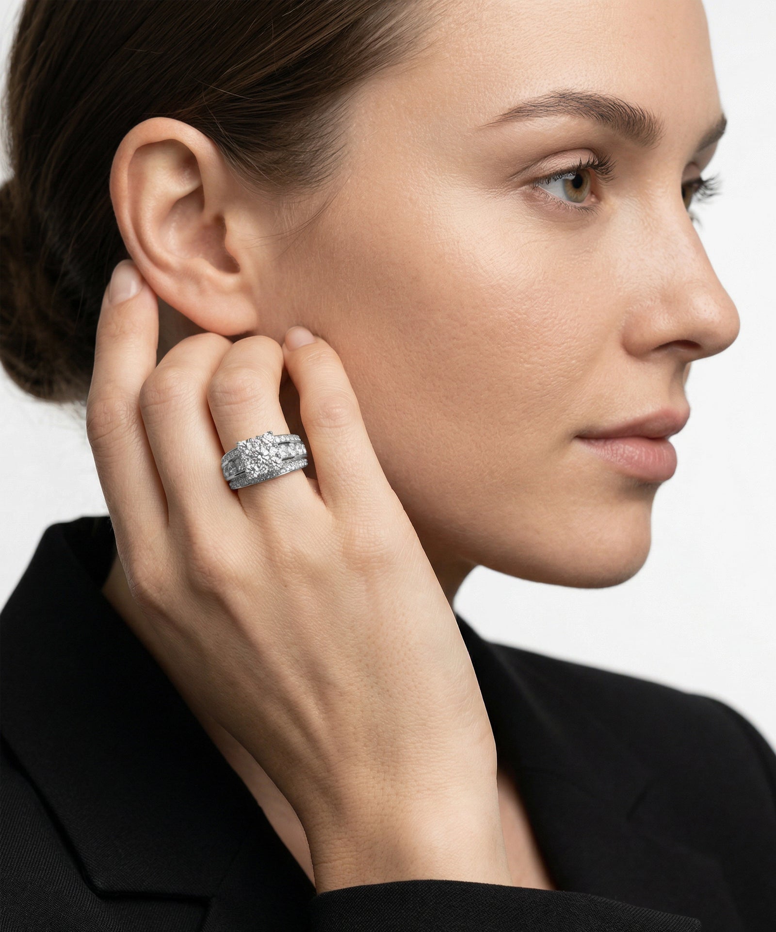 Woman wearing a silver earring and ring on a plain background