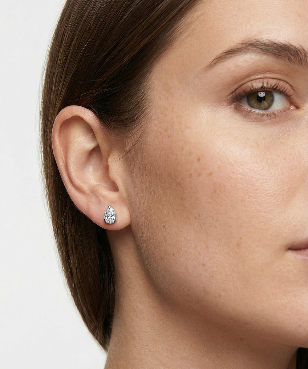 Close-up of a woman wearing a diamond earring on a white background