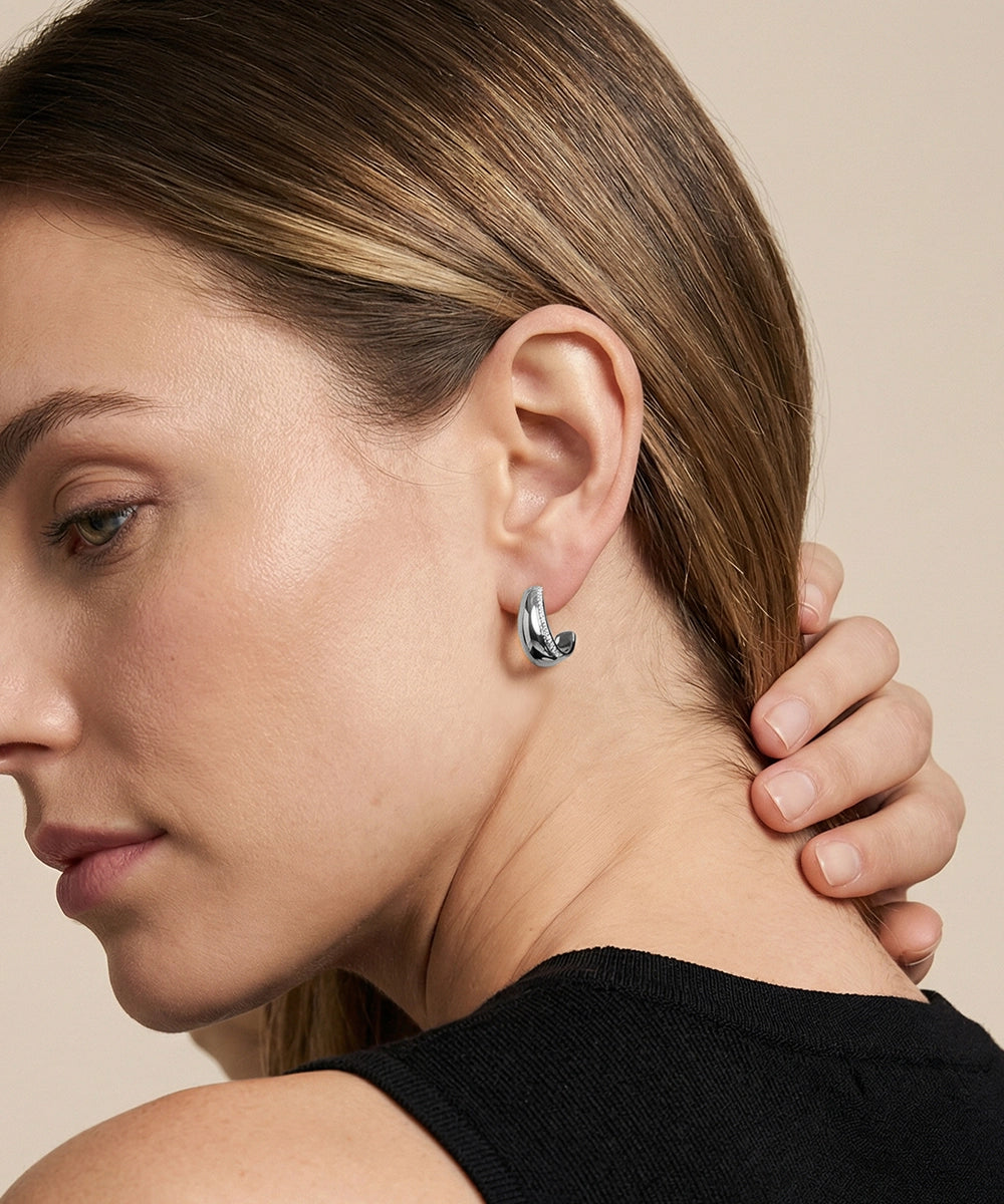 Close-up of a woman wearing a silver hoop earring with a neutral background